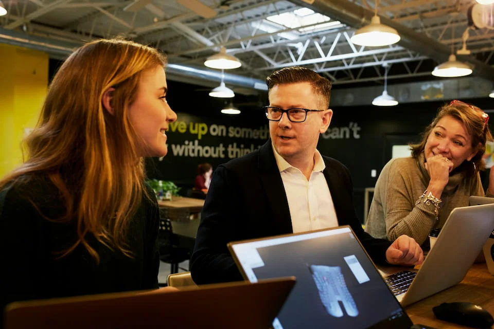 A man and two women are sitting next to the table.