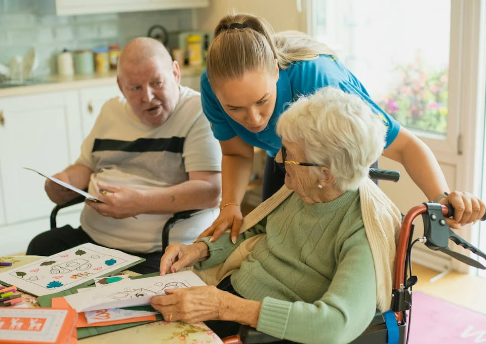 A caregiver helping an elderly couple with coloring.
